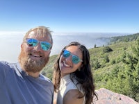 a man and woman taking a selfie in front of a mountain