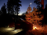 a car parked next to a campfire in the woods