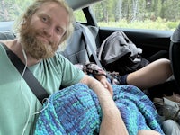 a man with a beard sitting in the back seat of a car