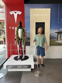 a man standing next to a tesla mannequin