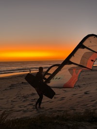 a person is standing on a beach with a windsurf board