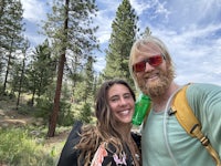 a man and woman taking a selfie in the woods