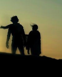 a silhouette of a man and woman walking on a hill